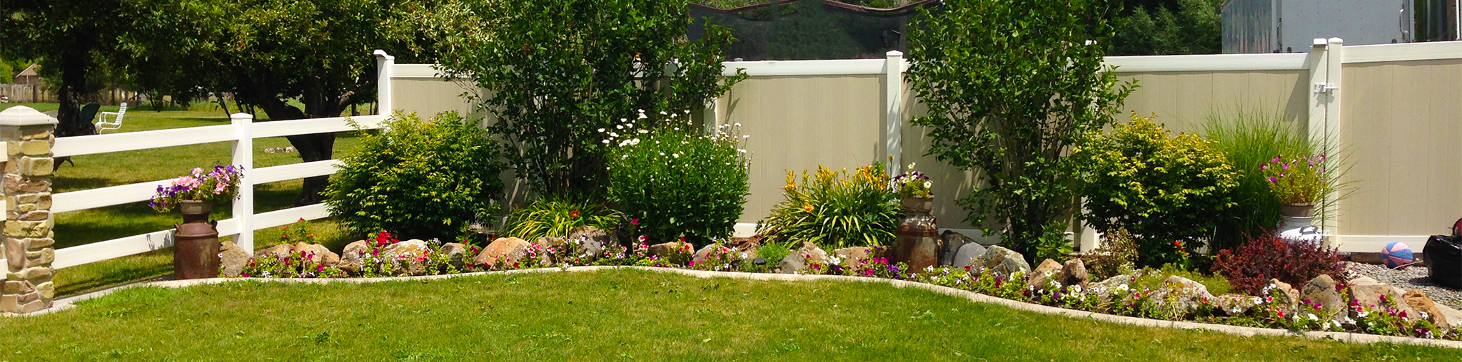 Two-Tone Vinyl Privacy Fence with Gate (on Right) Next to Flower Bed