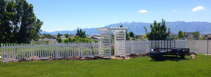 Vinyl picket fence in front of garden.