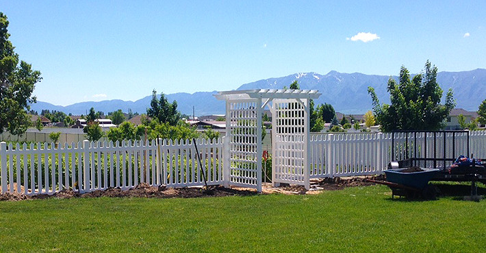 Vinyl picket fence in front of garden.